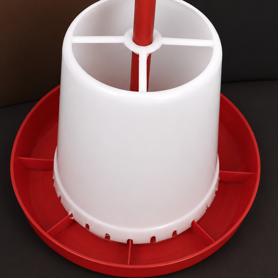 A plastic poultry feeder and super feeder with a white cylindrical body, red central post, and red circular base tray, shown on a dark background.